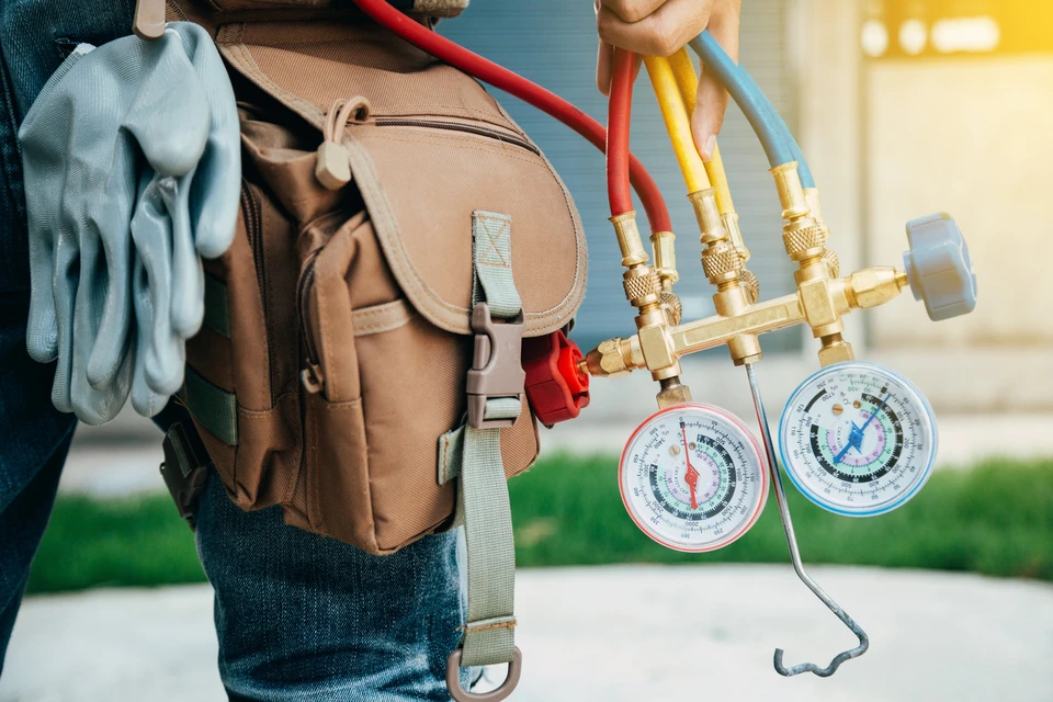 Extérieur résidentiel avec pompe à chaleur air-eau installée sur terrasse pavée contre mur de briques